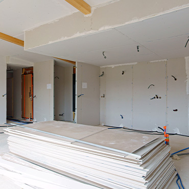 Chantier d'une maison, avec plaque de placo apparentes et plusieurs plaques posées au sol