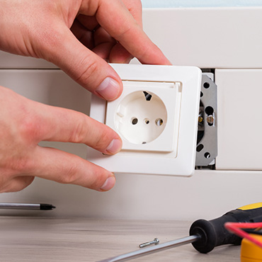 Photo représentant un électricien qui pose une prise électrique