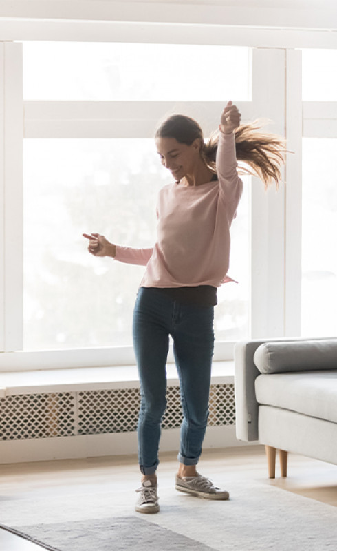 Photo d'une jeune femme qui danse dans son salon